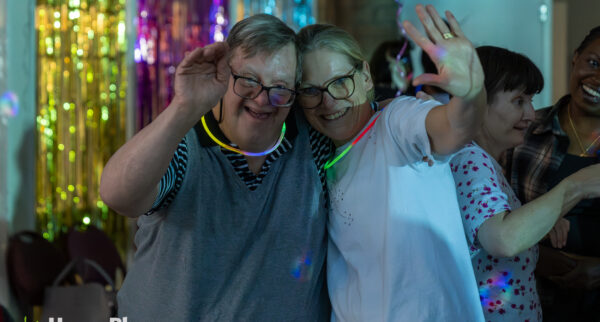 Julie with a HomePlace participant waving at HomePlace's disco party.