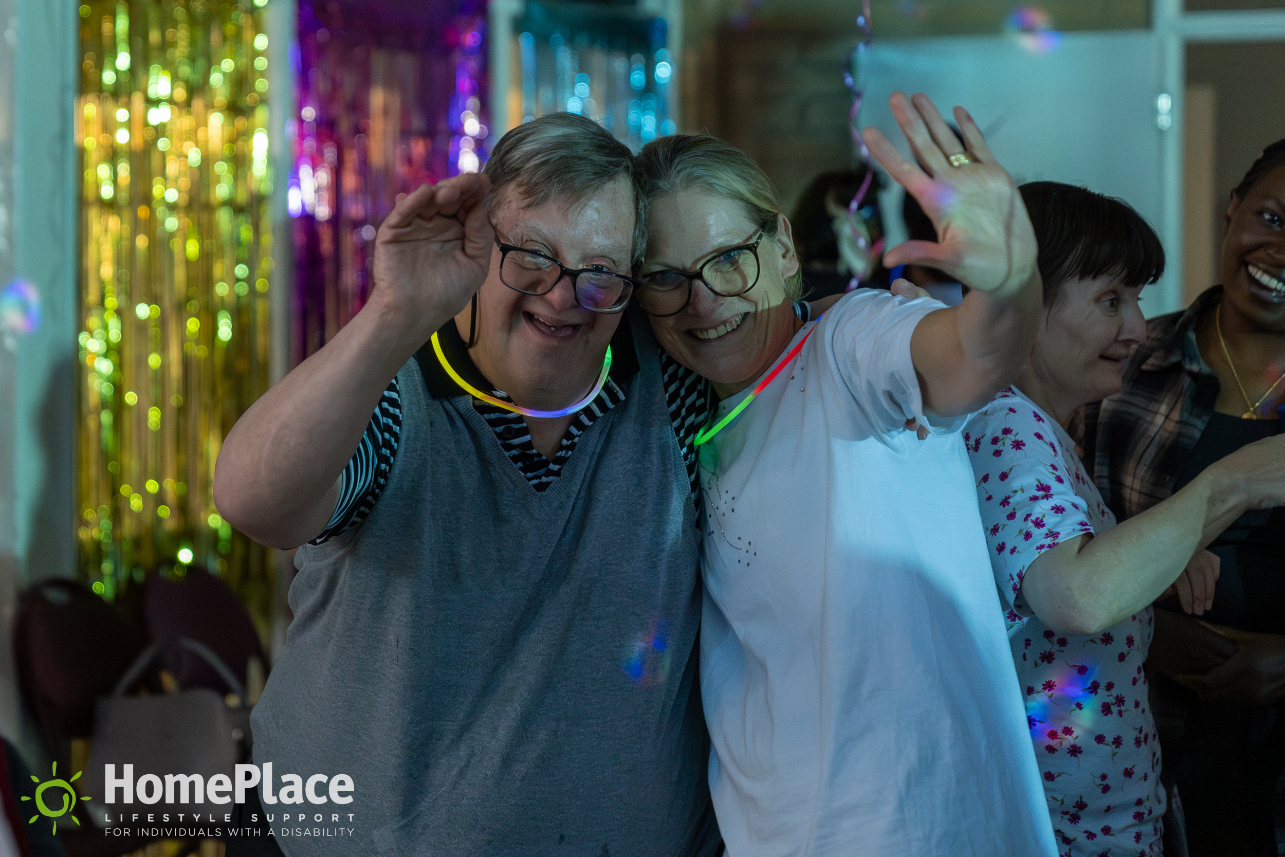 Julie with a HomePlace participant waving at HomePlace's disco party.
