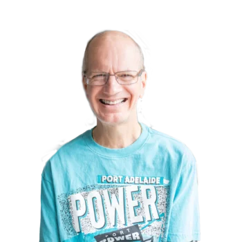 Participant Craig smiling. He is wearing silver metal glasses and a light blue Port Power tshirt.