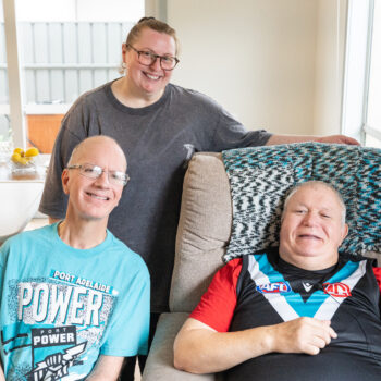 A portrait of Tommy and Craig in their new home with their support worker.